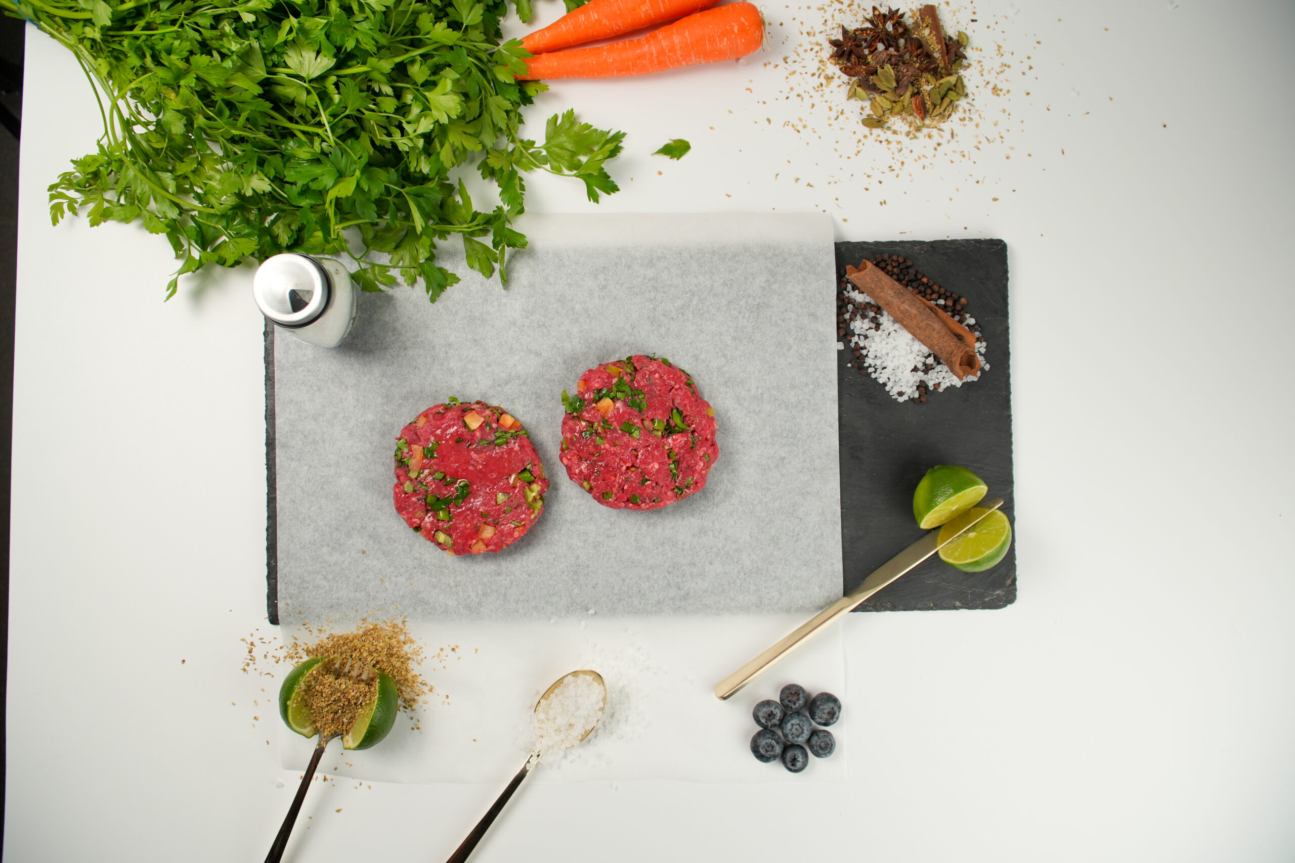 Raw halal lamb burger patties with herbs and spices on parchment paper