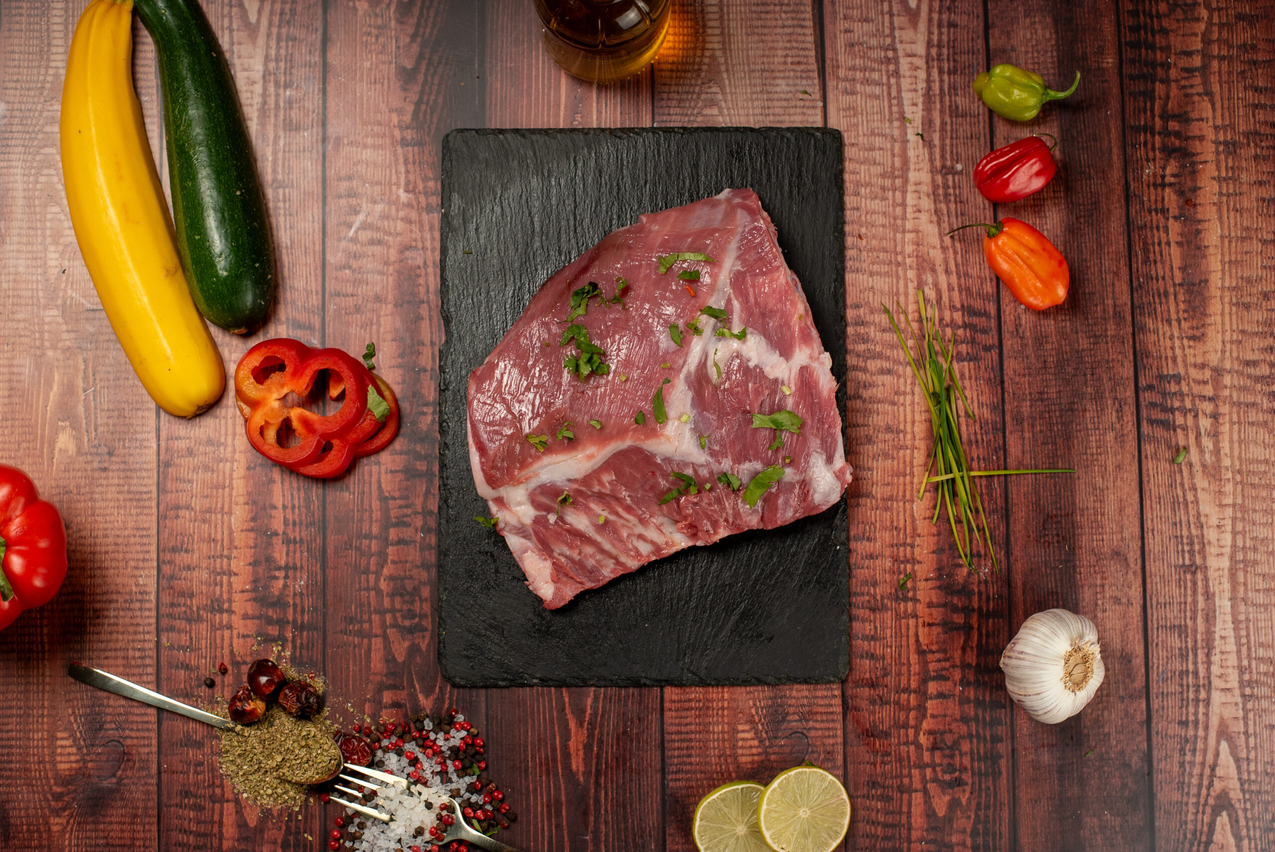 Raw halal lamb shoulder prepared with herbs on wooden background